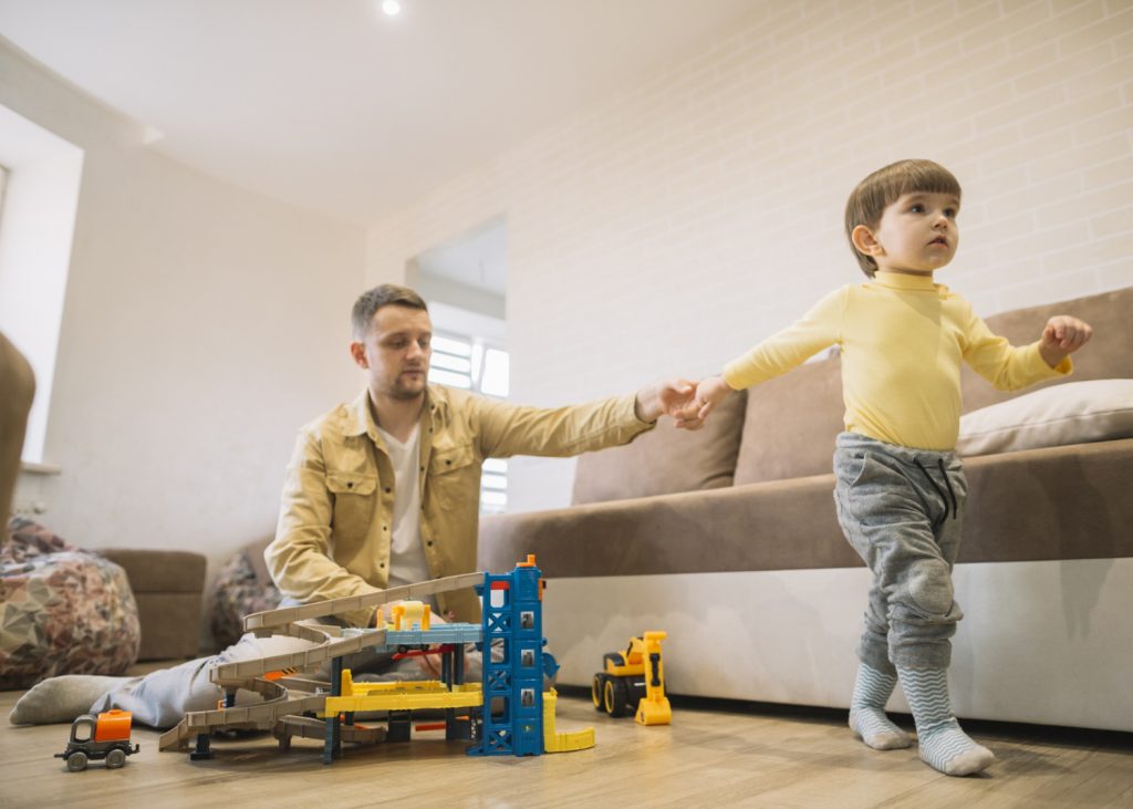 Father and son playing in living room together with toys during supervised parenting time